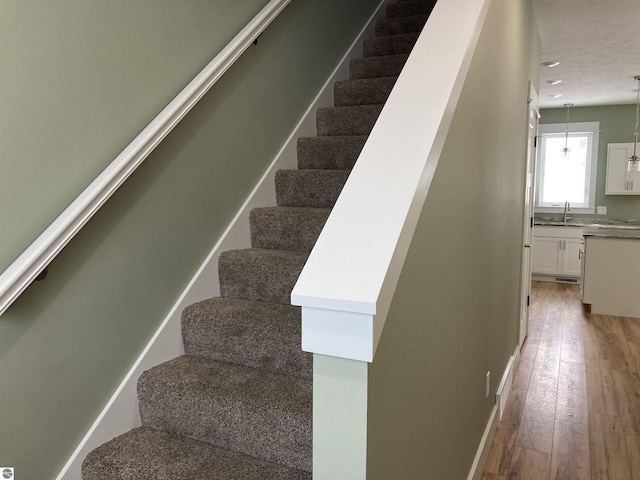 stairway featuring wood-type flooring and sink