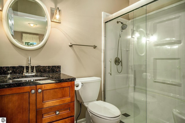 bathroom with vanity, toilet, and a shower with door