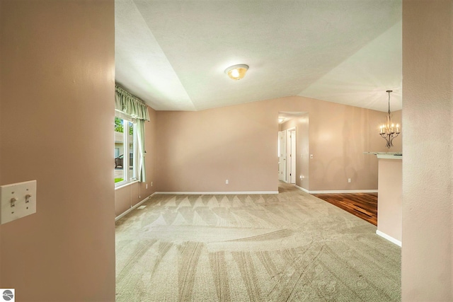 unfurnished room with carpet flooring, an inviting chandelier, and lofted ceiling