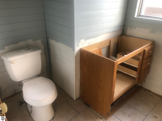 bathroom featuring tile patterned flooring, toilet, and wood walls