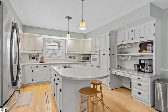 kitchen with stainless steel appliances, a kitchen island, tasteful backsplash, a kitchen bar, and white cabinets