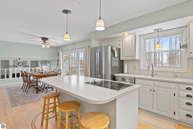 kitchen featuring backsplash, stainless steel appliances, sink, white cabinets, and a center island