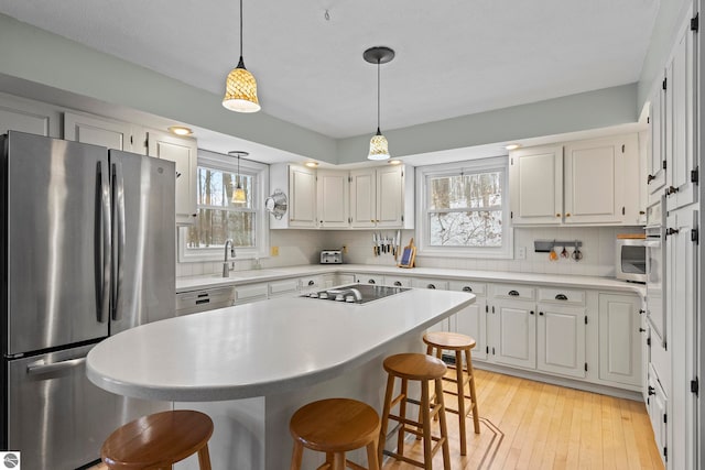 kitchen featuring sink, black electric cooktop, tasteful backsplash, white cabinetry, and stainless steel refrigerator