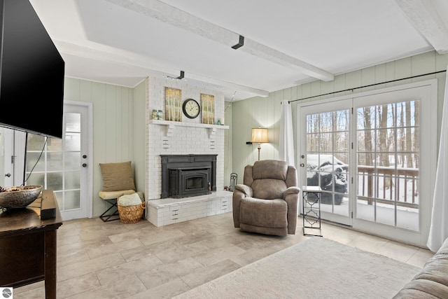 living room featuring beamed ceiling, wood walls, and a brick fireplace