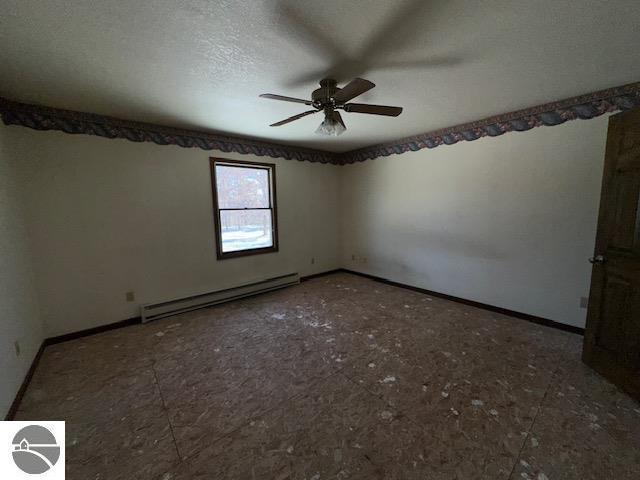 spare room featuring ceiling fan, a textured ceiling, and a baseboard heating unit