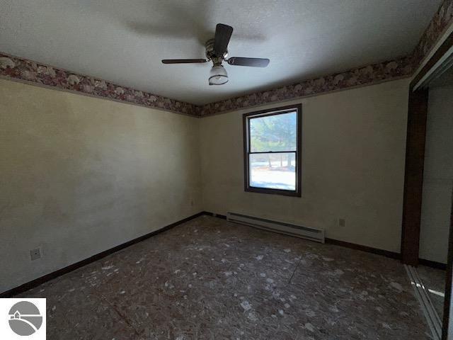 empty room with ceiling fan and baseboard heating