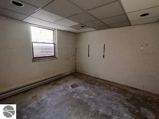 basement with a paneled ceiling and a baseboard radiator