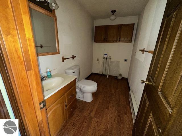 bathroom with hardwood / wood-style floors, vanity, toilet, and a baseboard heating unit