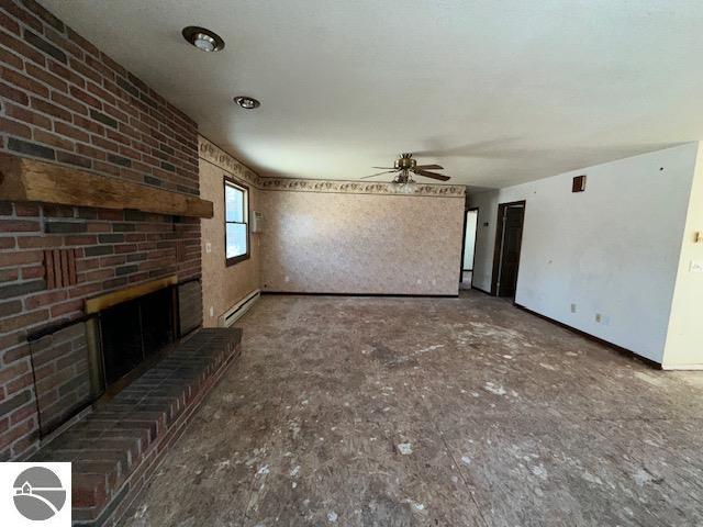 unfurnished living room with ceiling fan, a baseboard radiator, and a brick fireplace