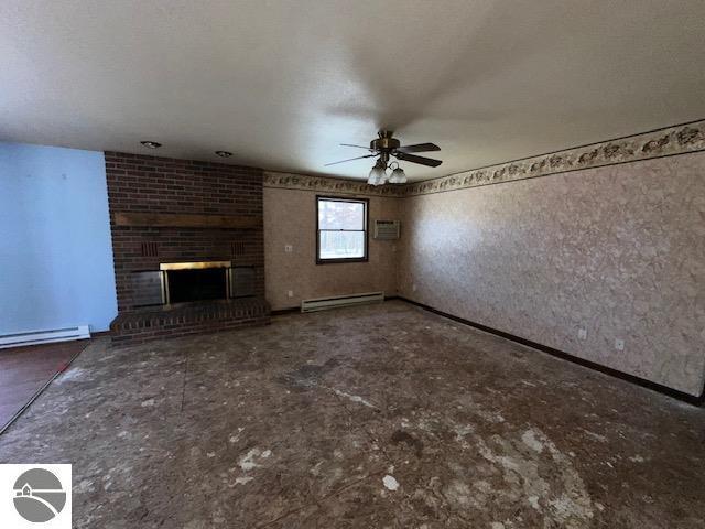 unfurnished living room with a fireplace, a baseboard radiator, a wall mounted air conditioner, and ceiling fan