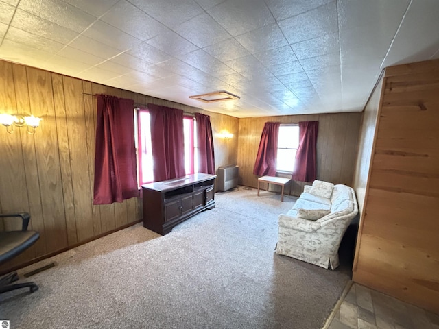 sitting room with light carpet and wood walls