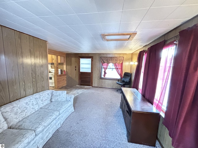 carpeted living room featuring wooden walls