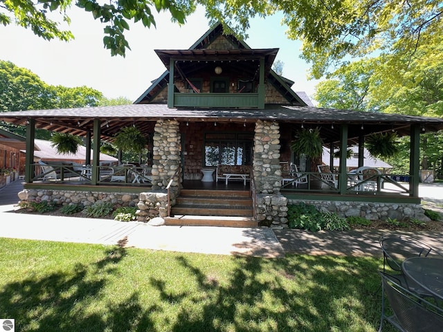 view of front facade featuring covered porch, a balcony, and a front yard