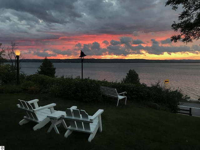 yard at dusk featuring a water view