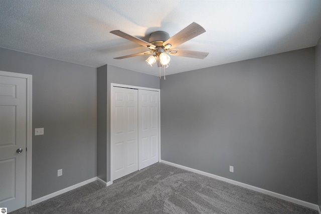 unfurnished bedroom featuring ceiling fan, dark carpet, a textured ceiling, and a closet