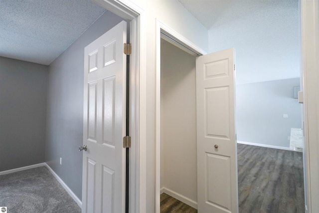 corridor featuring a textured ceiling and dark wood-type flooring