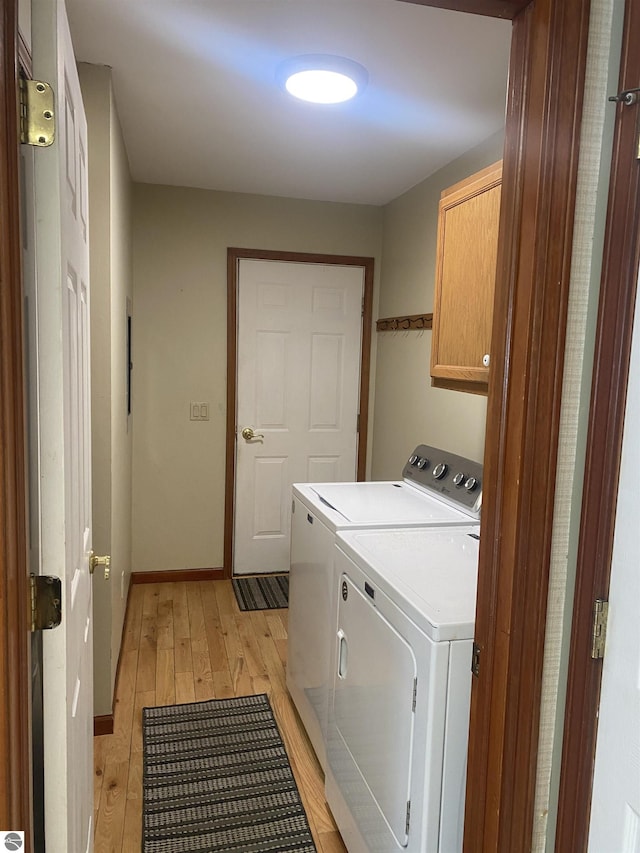 laundry room with cabinets, separate washer and dryer, and light wood-type flooring