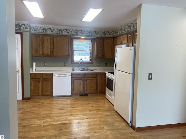 kitchen with sink, white appliances, and light hardwood / wood-style flooring