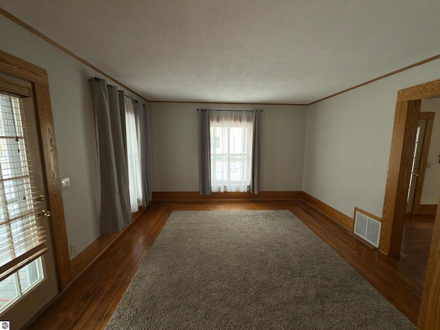 unfurnished room featuring a textured ceiling, dark hardwood / wood-style flooring, and ornamental molding