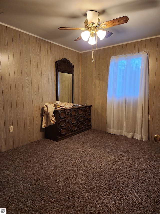 unfurnished bedroom with carpet floors, ceiling fan, and wooden walls