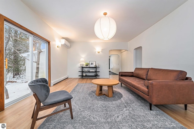 living room featuring a baseboard heating unit, hardwood / wood-style flooring, and a wall mounted air conditioner