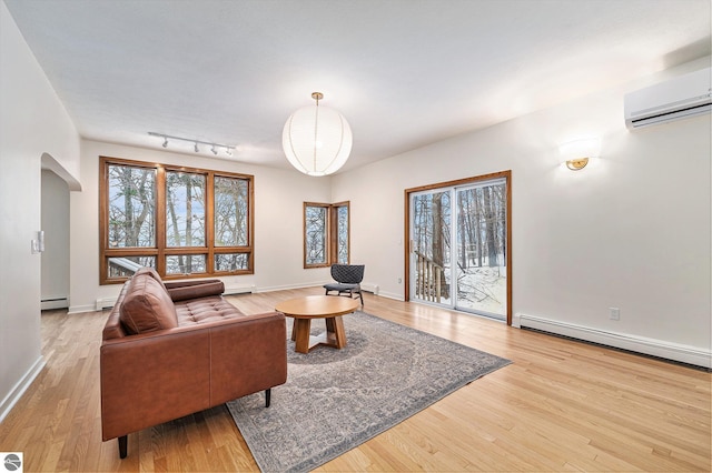 living room featuring a wall unit AC, rail lighting, light hardwood / wood-style floors, and a baseboard radiator