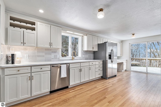 kitchen featuring light wood-type flooring, stainless steel appliances, backsplash, and white cabinetry