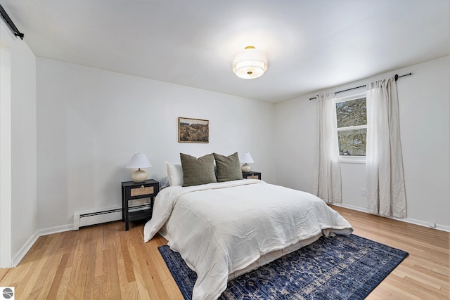 bedroom with a baseboard heating unit and hardwood / wood-style floors