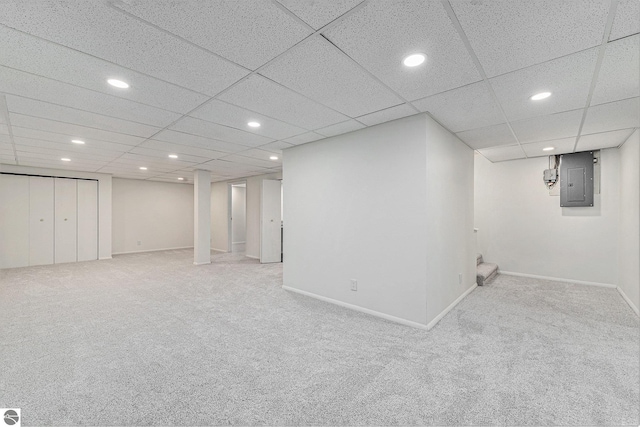 basement featuring a paneled ceiling, electric panel, and carpet floors