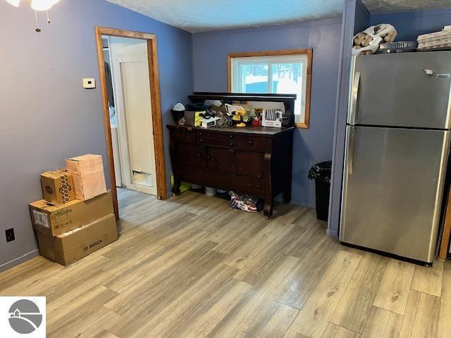 kitchen with dark brown cabinetry, ceiling fan, stainless steel fridge, light hardwood / wood-style floors, and a textured ceiling