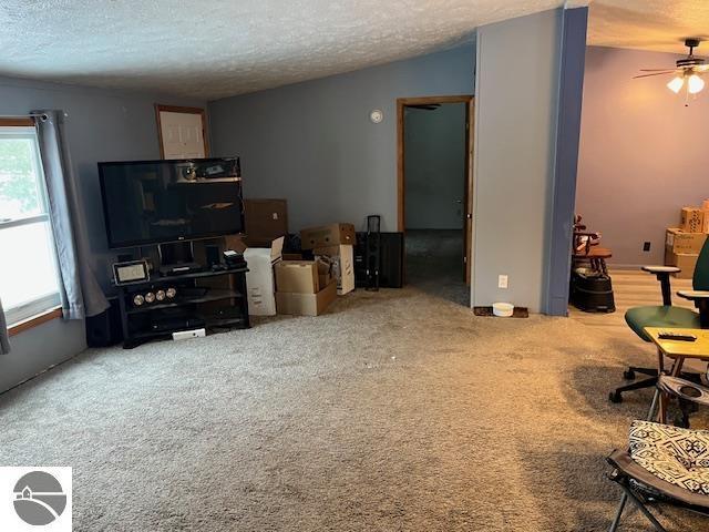 living room with ceiling fan, carpet floors, a textured ceiling, and vaulted ceiling