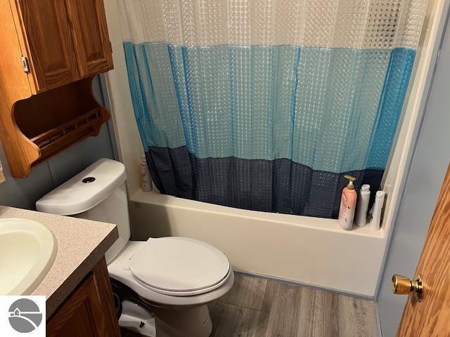 full bathroom with hardwood / wood-style flooring, vanity, toilet, and shower / bathtub combination with curtain