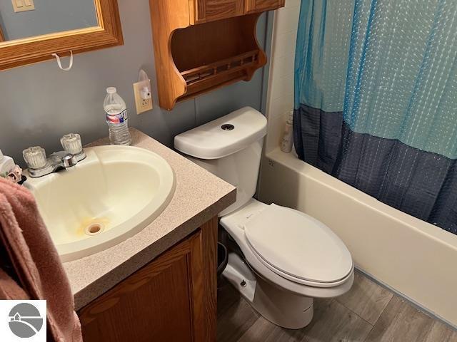 full bathroom with shower / tub combo with curtain, vanity, wood-type flooring, and toilet