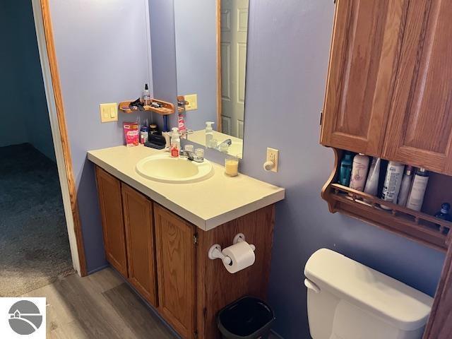 bathroom with hardwood / wood-style floors, vanity, and toilet