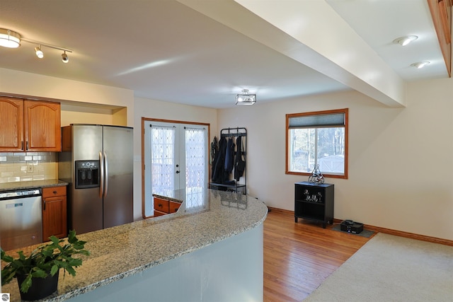 kitchen featuring light stone countertops, appliances with stainless steel finishes, backsplash, french doors, and light wood-type flooring