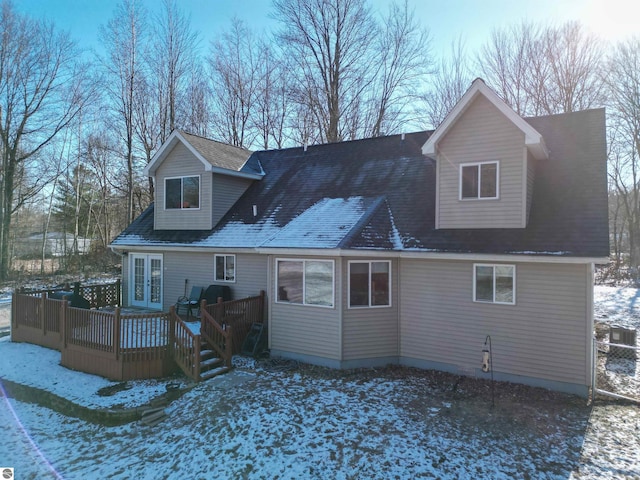 snow covered house with french doors and a wooden deck