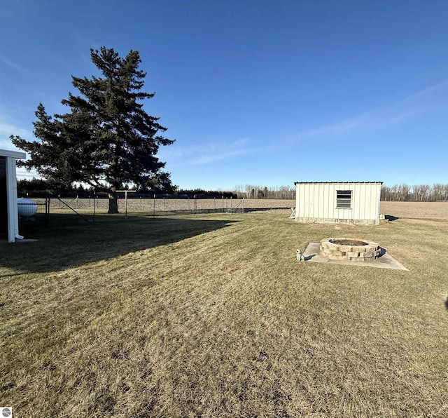 view of yard with a rural view, an outdoor fire pit, and a storage shed