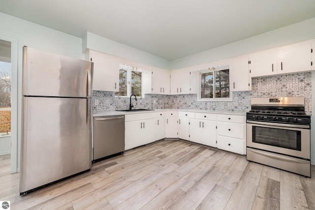 kitchen with light hardwood / wood-style floors, sink, white cabinetry, and stainless steel appliances