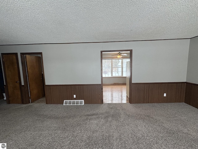 carpeted spare room featuring ceiling fan and a textured ceiling