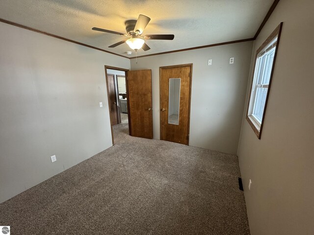 unfurnished bedroom featuring carpet flooring, ceiling fan, crown molding, and a textured ceiling