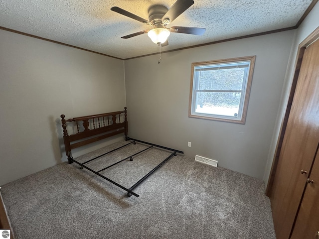 unfurnished bedroom with carpet flooring, ceiling fan, a textured ceiling, and ornamental molding