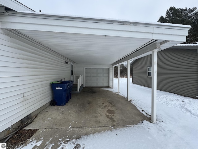 snow covered parking area with a garage and a carport