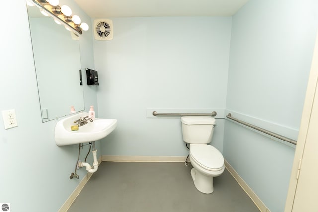 bathroom featuring sink, concrete flooring, and toilet