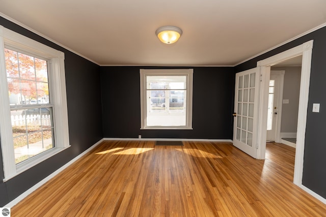 unfurnished room with light hardwood / wood-style floors, ornamental molding, and a wealth of natural light