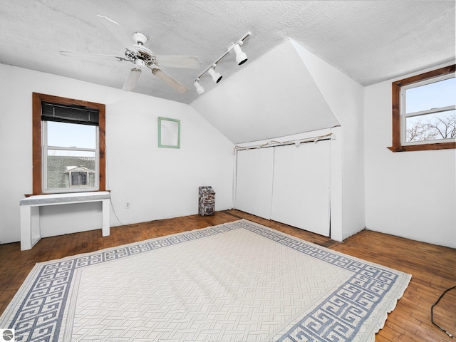 additional living space featuring lofted ceiling, ceiling fan, wood-type flooring, and a textured ceiling