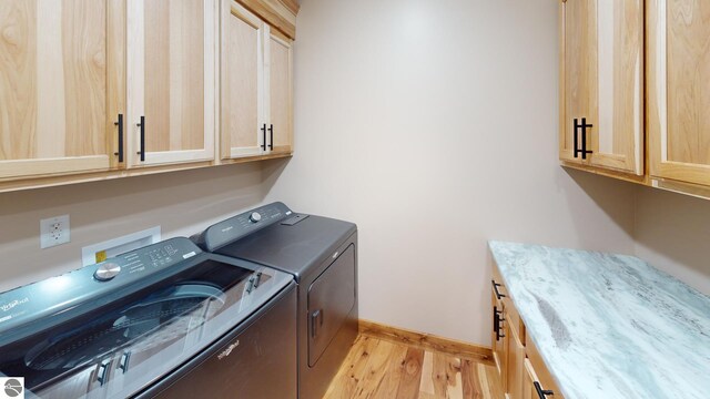 108 Rolling Oak Ln, Roscommon, MI 48653 - laundry room with washer and clothes dryer, light wood-style floors, cabinet space, and baseboards