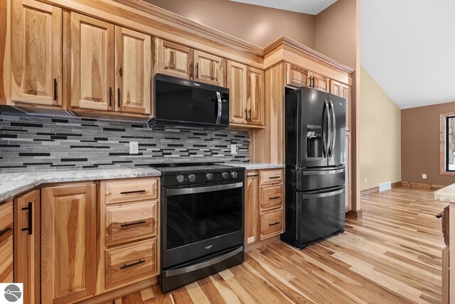 108 Rolling Oak Ln, Roscommon, MI 48653 - kitchen with visible vents, light wood-style flooring, tasteful backsplash, light stone counters, and black appliances