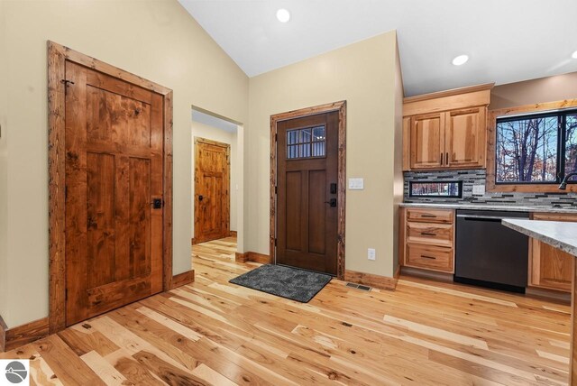 108 Rolling Oak Ln, Roscommon, MI 48653 - kitchen featuring vaulted ceiling, light countertops, backsplash, dishwasher, and light wood-style floors