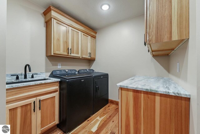 108 Rolling Oak Ln, Roscommon, MI 48653 - laundry area featuring light wood-type flooring, cabinet space, a sink, and washer and dryer