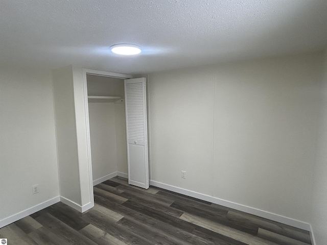 unfurnished bedroom featuring dark hardwood / wood-style flooring, a textured ceiling, and a closet